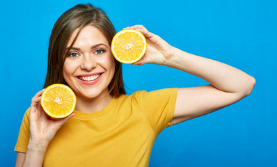 Happy young woman holding two orange fruit halves.