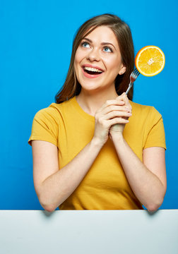 Smiling woman holding orange on fork.