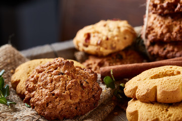 Conceptual composition with assortment of cookies and cinnamon on a wooden barrel, selective focus, close-up