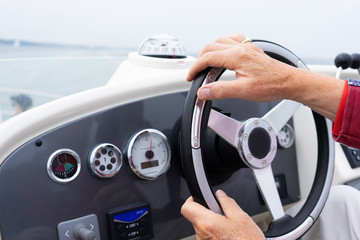hand steering a motor cruiser on the sea