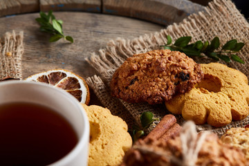 Traditional Christmas tea concept with a cup of hot tea, cookies and decorations on a wooden background, selective focus