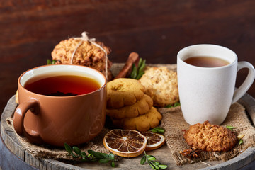 Traditional Christmas tea concept with a cup of hot tea, cookies and decorations on a wooden background, selective focus