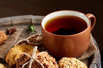 Traditional Christmas tea concept with a cup of hot tea, cookies and decorations on a wooden background, selective focus