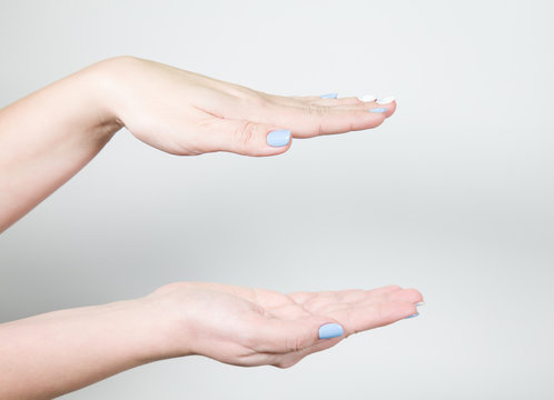 Closeup view of two female hands holding something invisible isolated on white background. Horizontal color photography.