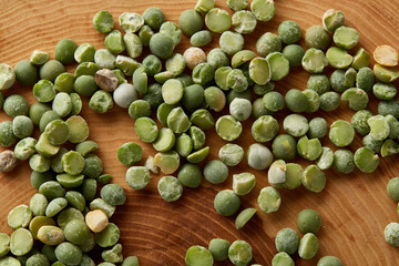 Pile of green peas on rustic wooden background, close-up, top view, selective focus.