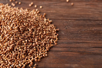 Pile of buckwheat groats on wooden background, top view, close-up, selective focus, shallow depth of field