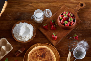 Delicious cake with fresh organic strawberries on cutting board over wooden background, close-up, selctive focus.