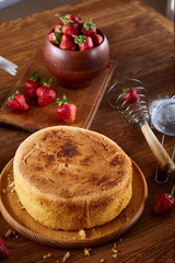 Delicious cake with fresh organic strawberries on cutting board over wooden background, close-up, selctive focus.