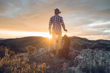Mountaineer with his dog in the mountains.guy and dog at sunset