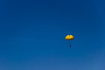 A man flying with a yellow parachute on a blue sky background