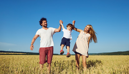 Happy family having fun playing in the field on a sunny summer day.