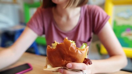 Close up of a hungry girl enjoying a fresh hamburger.