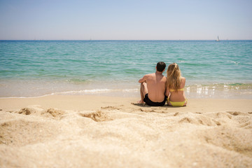 Fototapeta na wymiar couple sitting on a tropical beach facing the sea