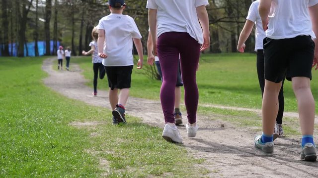 School age children run jogging during sport lesson in a green park in Wroclaw Poland