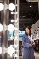 Young woman in a coat at the mirror