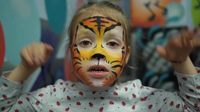 Body art painted face cute little girl on birthday theme party as a tiger