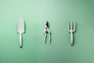 Gardening tools and utensils on green background. Top view with copy space. Pruner, rake, shovel for garden manteinance. Instruments for hobby. Eco garden, horticulture, farming, landscaping concept.