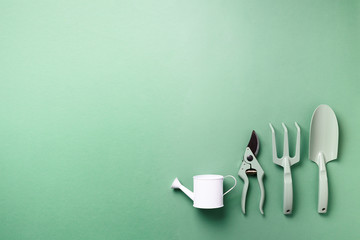 Gardening tools and utensils on green background. Top view with copy space. Pruner, rake, shovel,...