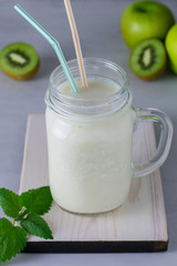 Smoothies with kiwi in a glass jar on a wooden board for lunch