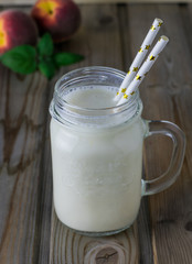 Smoothies in a glass jar on a wooden table with peaches for breakfast