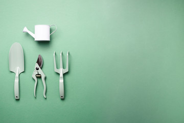 Gardening tools and utensils on green background. Top view with copy space. Pruner, rake, shovel, watering can for garden manteinance. Summer season. Farming, landscaping concept
