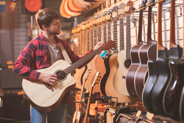 Jonge man met gitaar in een muziekwinkel