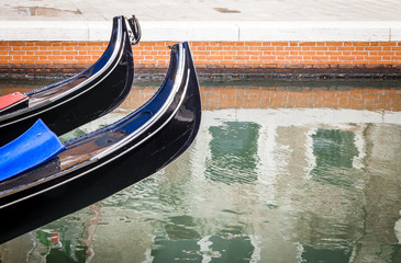 Fototapeta na wymiar Two Prows Of Venetian Gondolas Above Canal Waters