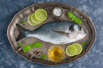 Fresh raw Dorado fish on a metal tray with ingredients for cooking, top view, horizontal