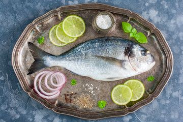 Fresh raw Dorado fish on a metal tray with ingredients for cooking, top view, horizontal