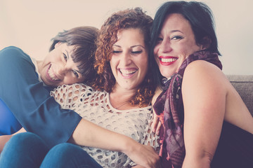 cheerful females middle age young womane friends together sitting on a sofa at home in leisure...