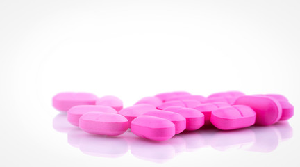Obraz na płótnie Canvas Pile of pink tablets pill isolated on white background. Norfloxacin 400 mg for treatment cystitis. Antibiotics drug resistance. Pink pills symbol of romantic love and healthcare for perfect couple.