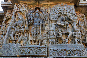 Fototapeta na wymiar Ornate wall panel reliefs depicting from left Deity playing damaru, Vishnu and dancing Sarswati, Hoysaleshwara temple, Halebidu, Karnataka