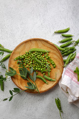 Fresh green peas on wooden plate