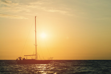 Yacht at sea in the background of a sunset with descended sails