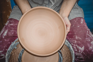 Master Potter holds round clay plate in his hands. Sculptor sculpts pots products from white clay. Workshop pottery. Master crock. Art, creativity. Cultural traditions. Handmade. Craft.