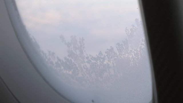 Close-up shot of illuminator with frozen glass, view from inside flying airplane