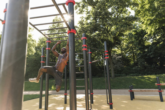 Muscular young man exercising on parkour bars