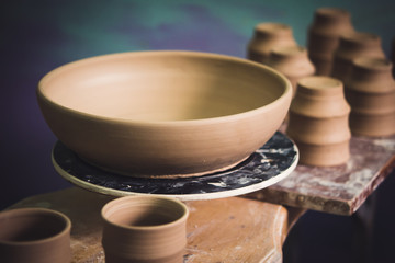 Ceramic clay products stand on the shelf close-up. Sculptor sculpts pots products from white clay. Dark. Workshop pottery. Master crock. Cultural traditions. Handmade. Craft. Twisted potter's wheel.