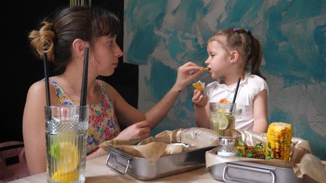 Young mother and child girl daughter eating nachos with sause in Mexican cuisine food restaurant