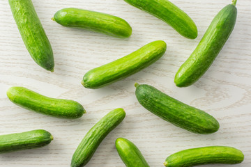 Fresh mini cucumbers flatlay on grey wood background.