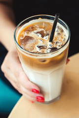 Iced coffee latte. Iced coffee with milk. Woman holding glass cup of iced coffee. Coffee time in summer day. Morning mood. Top view