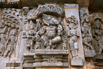 Ornate wall panel reliefs depicting from left Kamdev and his wife Rati, and dancing Ganesha. Kedareshwara temple, Halebidu, Karnataka