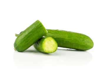Sliced fresh green mini cucumbers one whole and two halves isolated on white background.