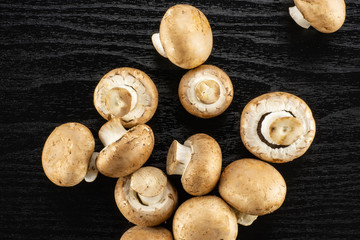 Raw fresh brown champignons table top on black wood background.