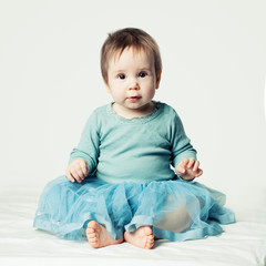 Fototapeta premium Cheerful baby girl sitting on white background. Beautiful child girl