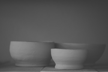 Ceramic clay products stand on the shelf close-up. Sculptor sculpts pots products from white clay. Dark. Workshop pottery. Master crock. Cultural traditions. Handmade. Craft. Twisted potter's wheel.