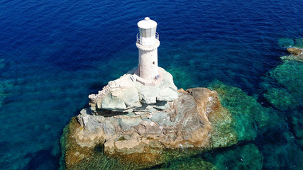 Aerial drone bird's eye view of iconic lighthouse of Tourlitis in port of Andros island chora,...