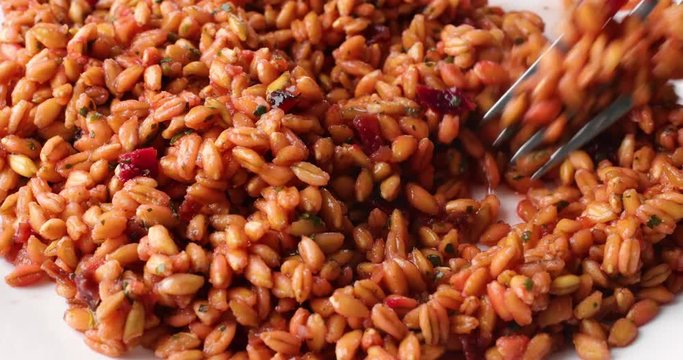 Video of stirring a plate of cooked farro with beets and spinach and seasonings with a fork then taking a forkful at the end.