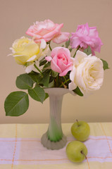 Still life of a bouquet of roses and green apples on a beige background