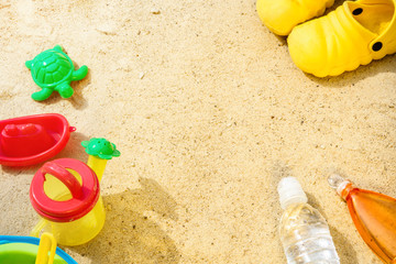 Fototapeta na wymiar Beach Summer Sun Sand Kids Toys and bottle water slippers and Sunscreen